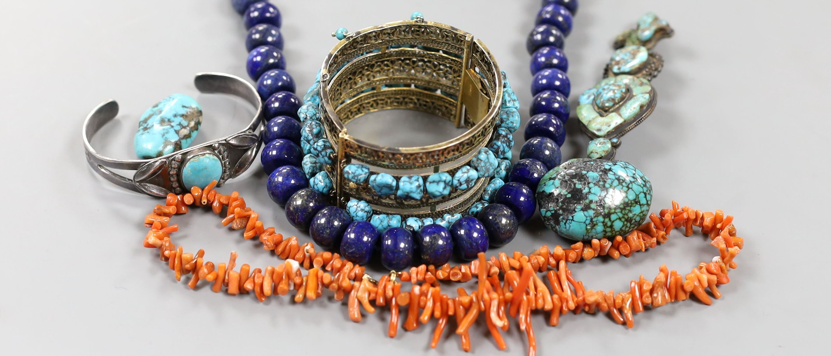 A lapis lazuli necklace, 48cm, a coral necklace and a group of turquoise set jewellery, including a gilt white metal two row hinged bangle and an antique pendant?.